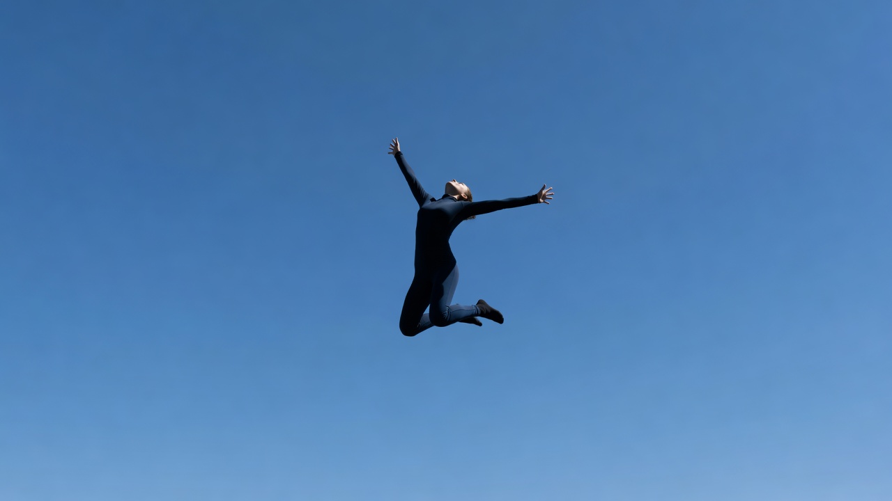 Abstract upward motion of a person jumping against a clear sky